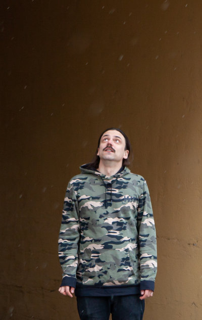 Mies seisoo lumisateessa, katsoo toiveikkaana tulevaisuuteen.